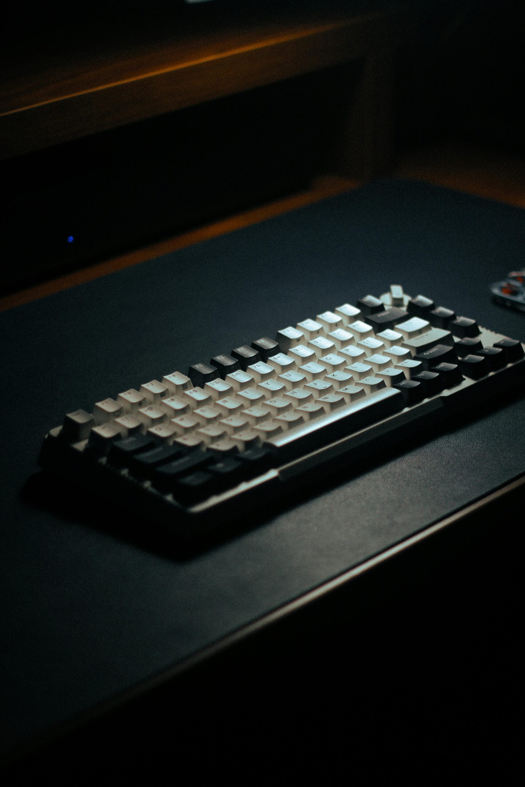 Modern mechanical keyboard with a minimalist design on a dimly lit desk, perfect for tech setups.